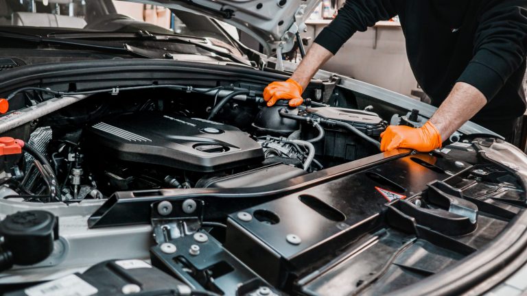 Mechanik povoluje nádrž na chladící kapalinu automobilu BMW