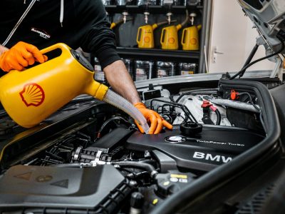 Mechanik doplňujíc olej Shell helix do BMW motoru. Je lit pomocí žluté nádoby na olej.